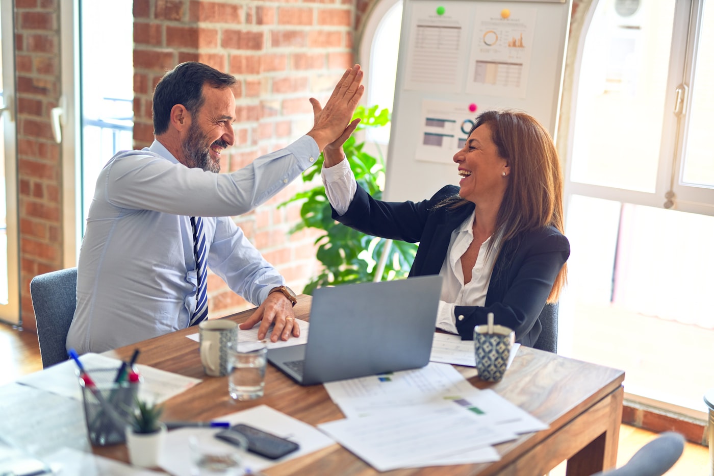 Zwei Menschen geben sich ein High-Five im Büro